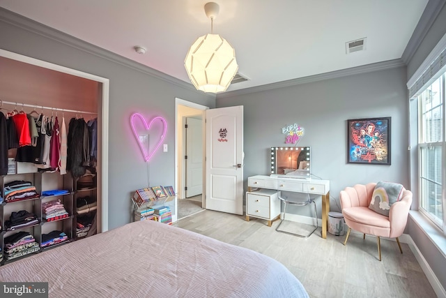 bedroom with crown molding, light hardwood / wood-style flooring, and a closet