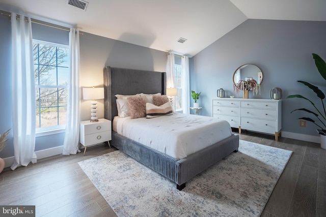 bedroom with multiple windows, dark wood-type flooring, and vaulted ceiling