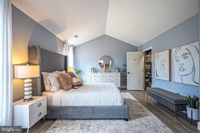 bedroom with dark wood-type flooring, a spacious closet, and vaulted ceiling