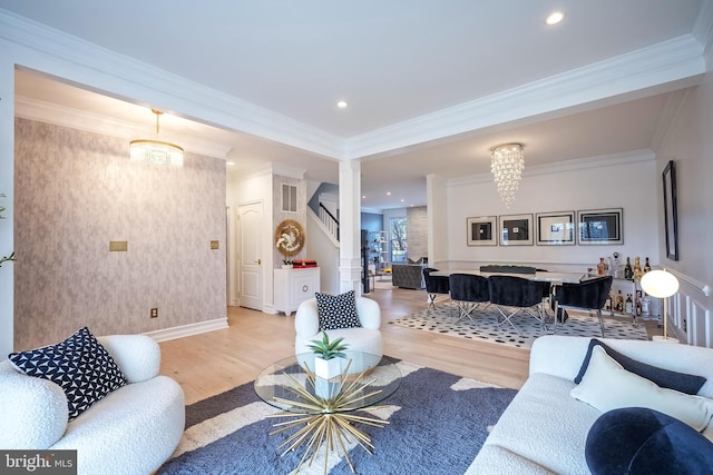 living room featuring crown molding, a chandelier, and light hardwood / wood-style floors