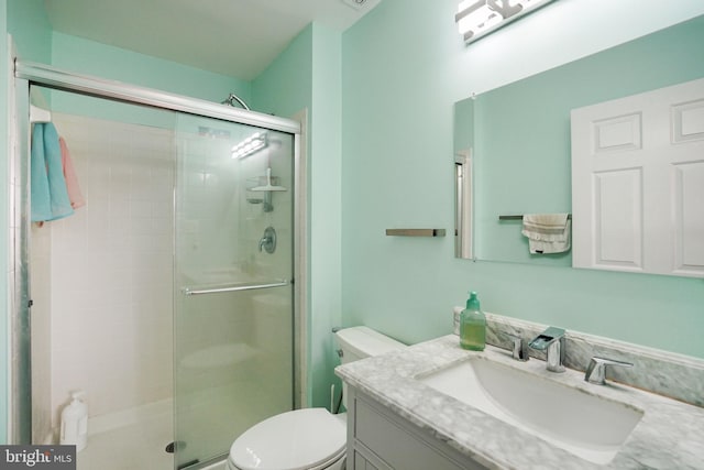 bathroom featuring vanity, a shower with shower door, and toilet