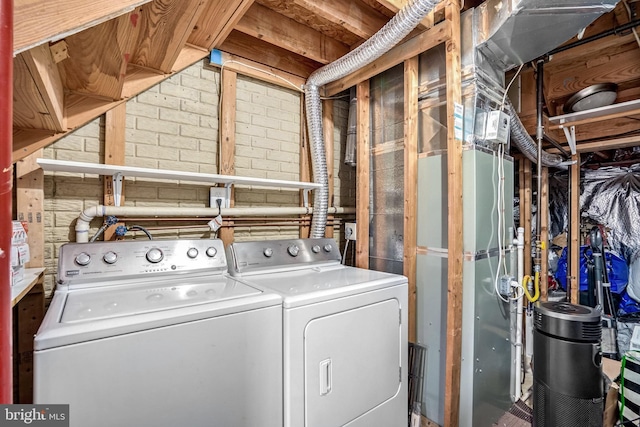 clothes washing area with brick wall and washer and clothes dryer