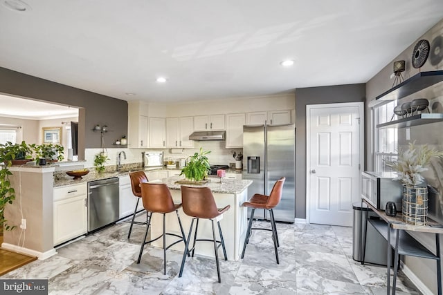 kitchen featuring a breakfast bar, stainless steel appliances, kitchen peninsula, and white cabinets