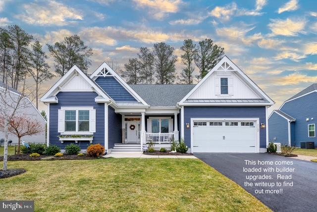 craftsman-style home featuring central AC unit, a garage, a front yard, and a porch