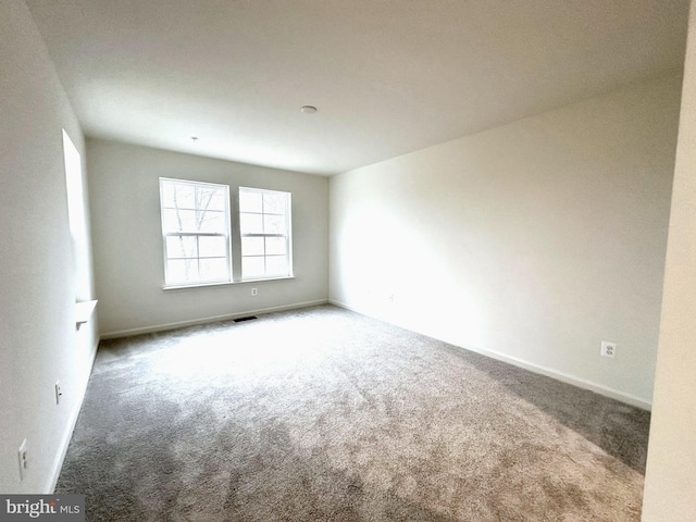 spare room with carpet, visible vents, and baseboards