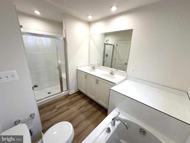 full bathroom featuring a stall shower, double vanity, a sink, and wood finished floors