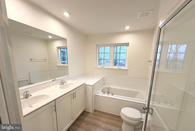 full bath with toilet, double vanity, visible vents, and a sink