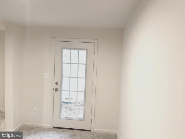 doorway to outside featuring baseboards and light colored carpet