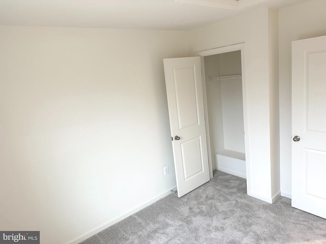 unfurnished bedroom featuring light carpet, baseboards, and a closet