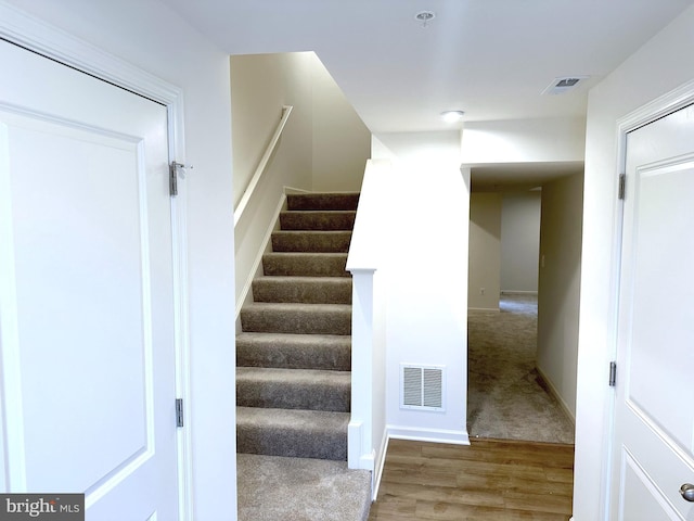 stairs featuring carpet, visible vents, baseboards, and wood finished floors