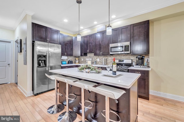 kitchen featuring hanging light fixtures, dark brown cabinets, stainless steel appliances, and a center island