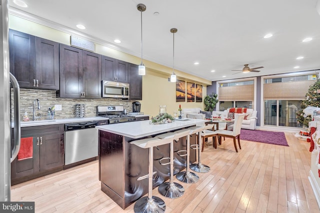 kitchen featuring sink, dark brown cabinets, stainless steel appliances, a center island, and decorative light fixtures