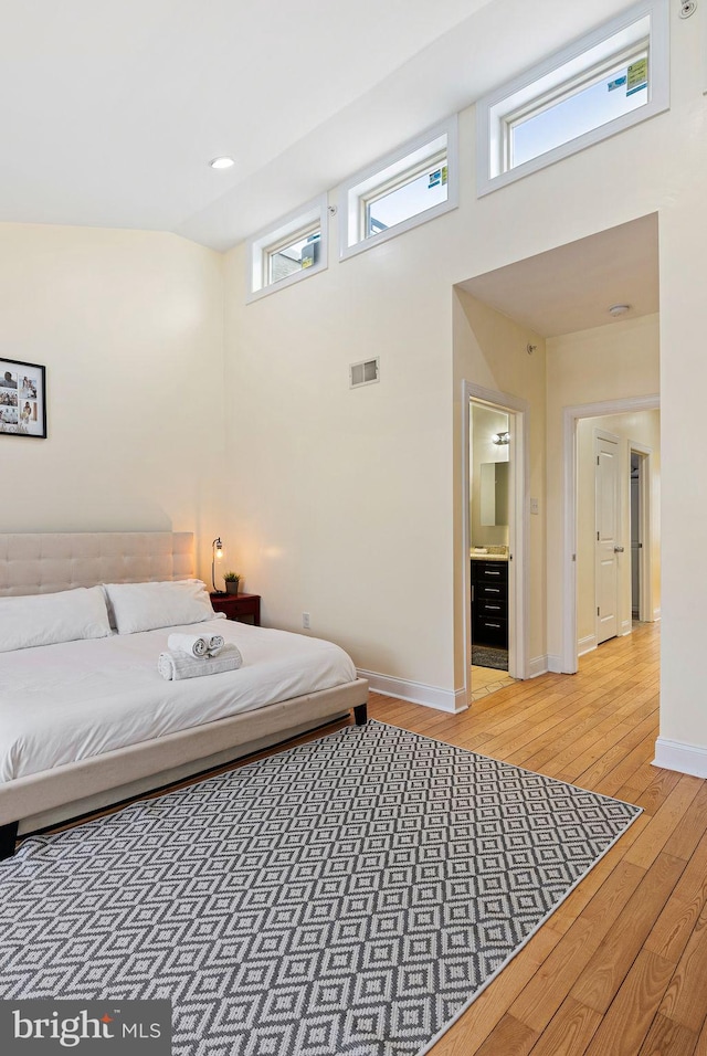 bedroom with a towering ceiling and wood-type flooring