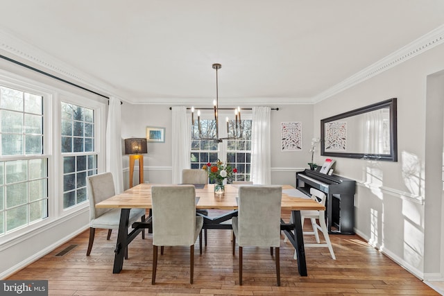 dining room featuring visible vents, baseboards, hardwood / wood-style flooring, ornamental molding, and an inviting chandelier