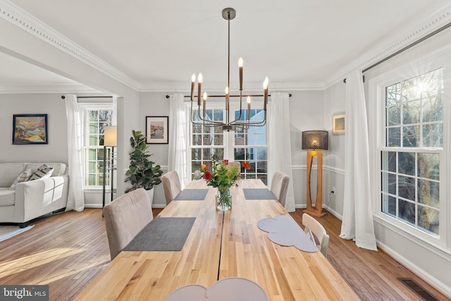 dining room featuring a chandelier, visible vents, ornamental molding, and hardwood / wood-style floors