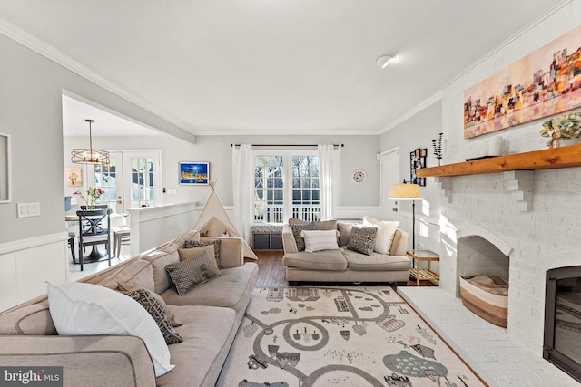 living area featuring wainscoting, a fireplace, and crown molding