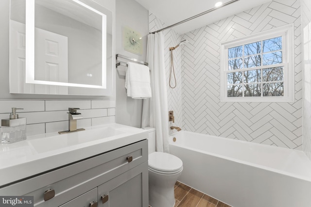 bathroom featuring toilet, wood finish floors, vanity, tasteful backsplash, and shower / bath combo with shower curtain