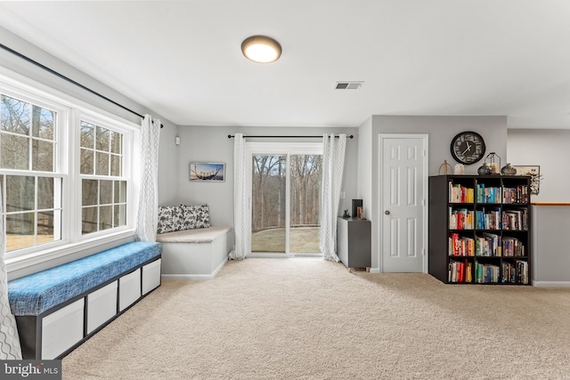 living area with baseboards, visible vents, and carpet flooring