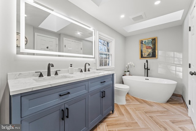 bathroom with double vanity, a freestanding bath, a sink, and recessed lighting