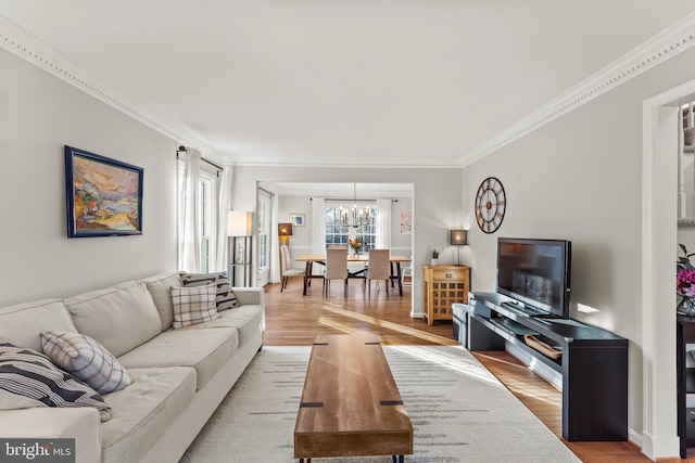 living area with ornamental molding, light wood-type flooring, and a notable chandelier