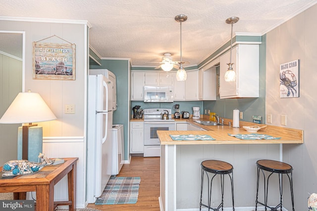 kitchen featuring sink, white appliances, a breakfast bar, white cabinets, and kitchen peninsula