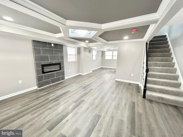 basement featuring a tile fireplace, ornamental molding, and hardwood / wood-style floors