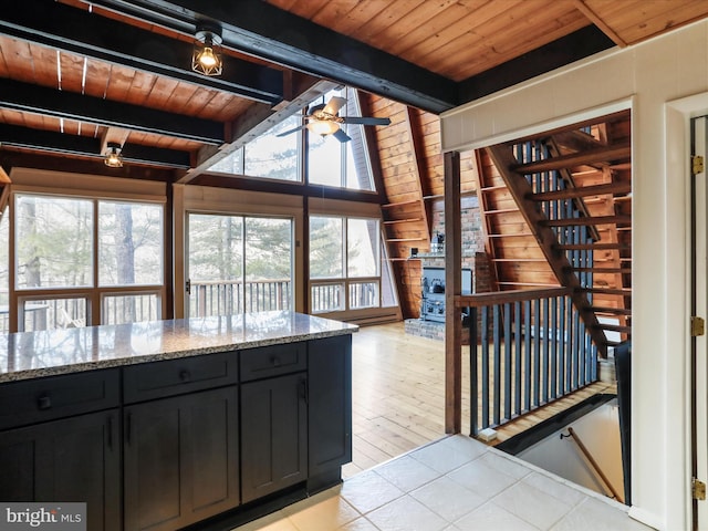 kitchen featuring wood ceiling, light stone counters, dark cabinets, and light tile patterned flooring