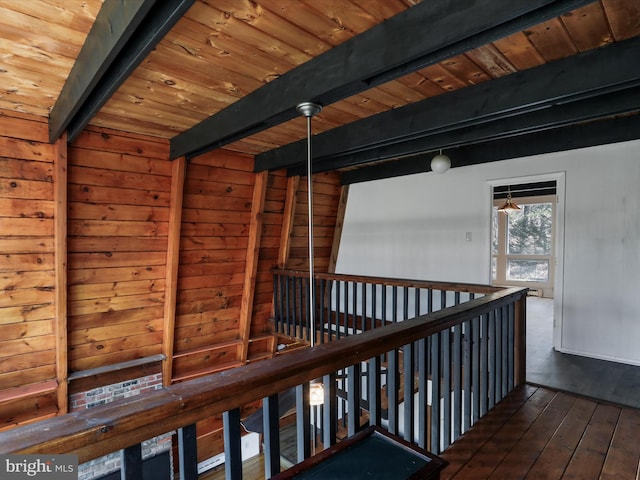 interior space featuring dark wood-style floors, an upstairs landing, wooden walls, beam ceiling, and wood ceiling