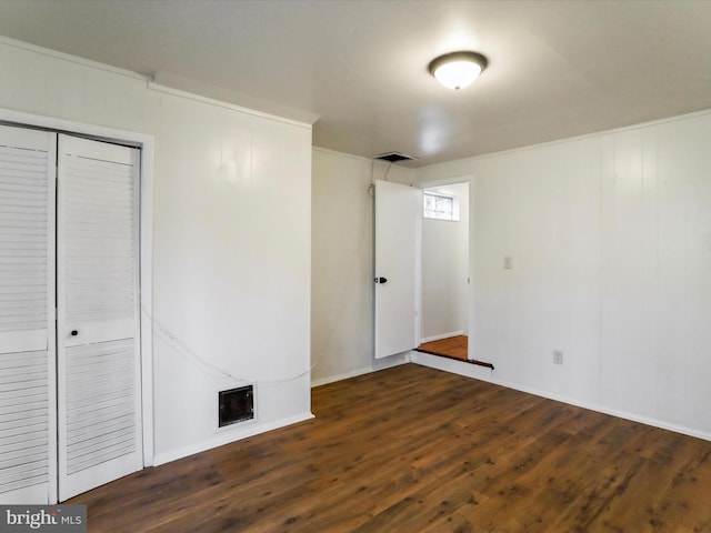 unfurnished bedroom with visible vents, dark wood-type flooring, and a closet