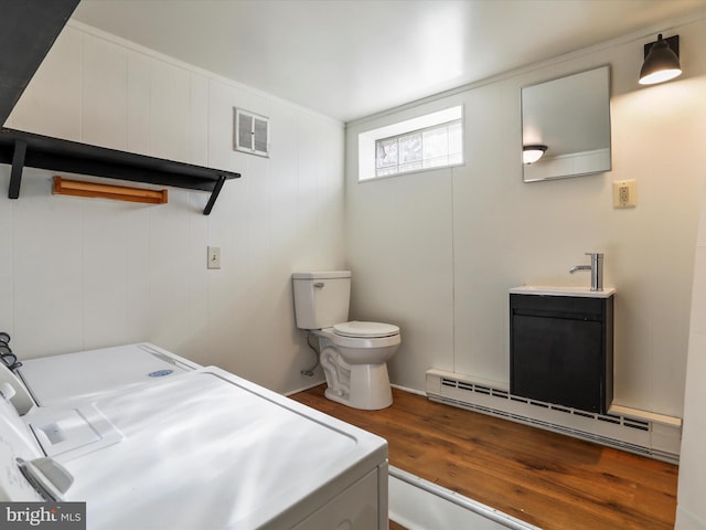 bathroom with vanity, a baseboard radiator, washing machine and dryer, wood finished floors, and visible vents