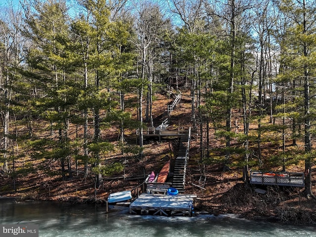 view of dock featuring a forest view, stairway, and a water view