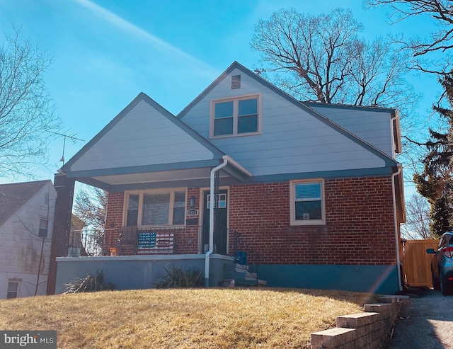 bungalow-style home with covered porch, brick siding, and a front yard