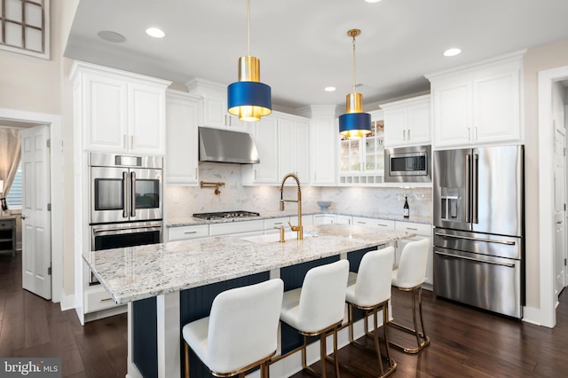 kitchen featuring sink, appliances with stainless steel finishes, white cabinetry, hanging light fixtures, and light stone counters