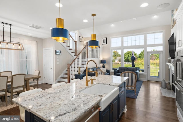 kitchen with sink, decorative light fixtures, dark hardwood / wood-style flooring, and an island with sink