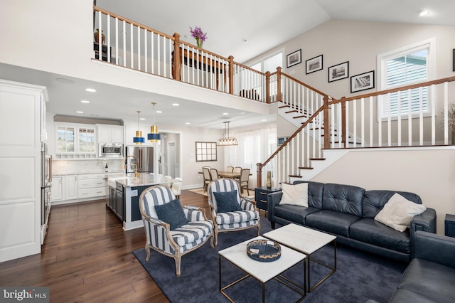 living room featuring high vaulted ceiling, sink, a wealth of natural light, and dark hardwood / wood-style flooring