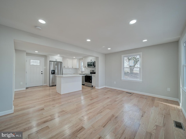 kitchen featuring a kitchen island, appliances with stainless steel finishes, sink, white cabinets, and light hardwood / wood-style flooring