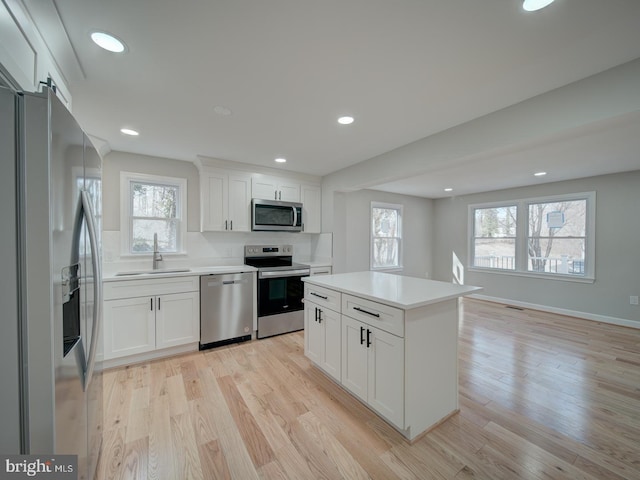 kitchen featuring stainless steel appliances, a center island, sink, and white cabinets