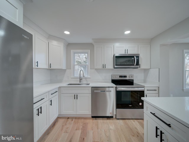 kitchen with white cabinetry, appliances with stainless steel finishes, sink, and light hardwood / wood-style flooring