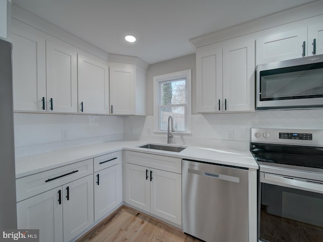 kitchen with stainless steel appliances, sink, decorative backsplash, and white cabinets