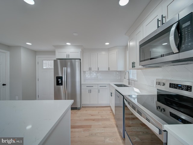 kitchen featuring appliances with stainless steel finishes, light stone countertops, sink, and white cabinets