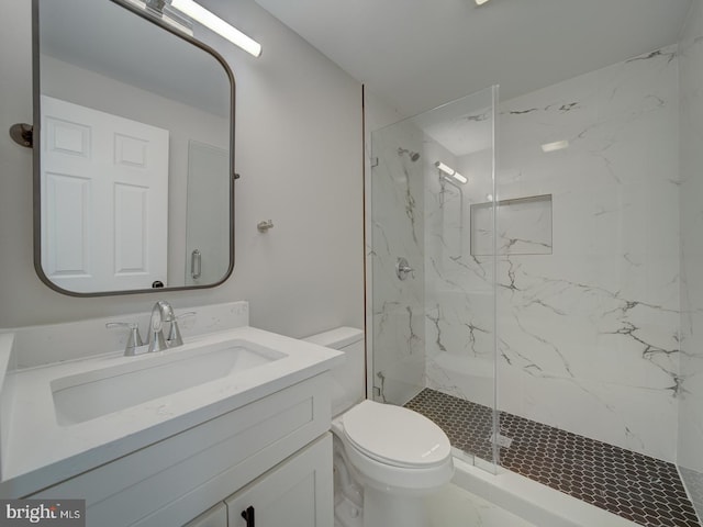 bathroom with vanity, toilet, and tiled shower