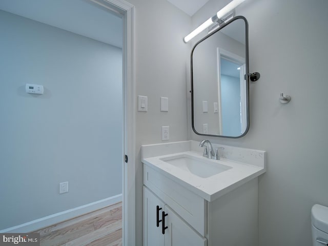 bathroom with wood-type flooring, vanity, and toilet