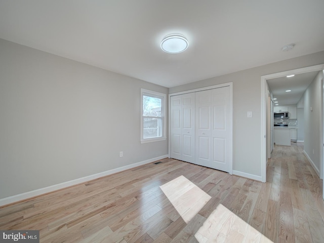 unfurnished bedroom with light hardwood / wood-style flooring and a closet