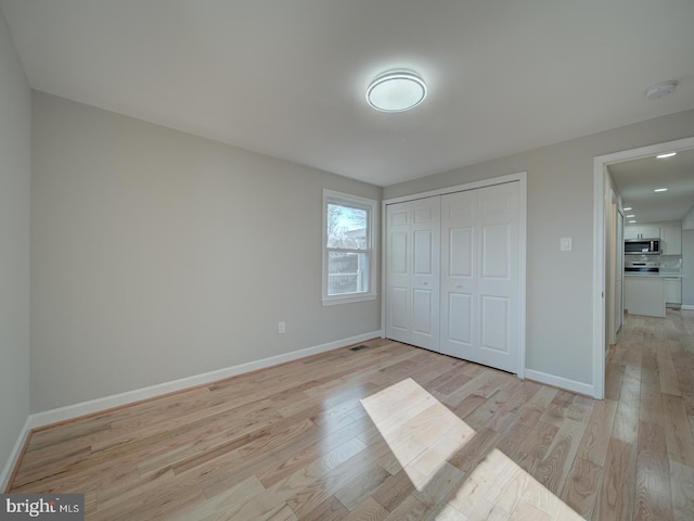 unfurnished bedroom with a closet and light wood-type flooring