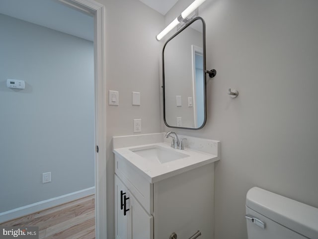 bathroom with hardwood / wood-style flooring, vanity, and toilet