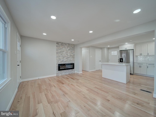 unfurnished living room with a stone fireplace and light hardwood / wood-style flooring