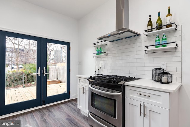 kitchen featuring stainless steel gas range oven, white cabinetry, dark hardwood / wood-style floors, island exhaust hood, and decorative backsplash