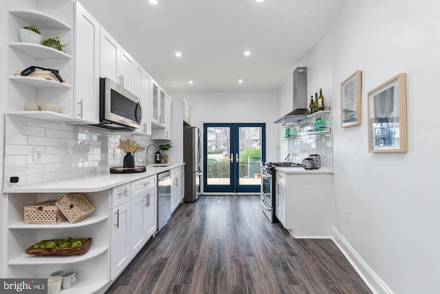 kitchen featuring dark hardwood / wood-style floors, white cabinets, wall chimney exhaust hood, stainless steel appliances, and french doors