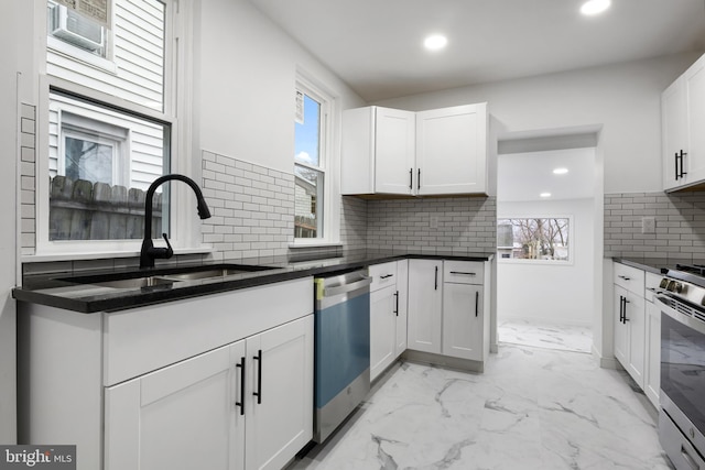 kitchen featuring sink, white cabinetry, dark stone countertops, stainless steel appliances, and tasteful backsplash