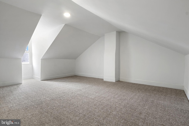 additional living space featuring vaulted ceiling and carpet